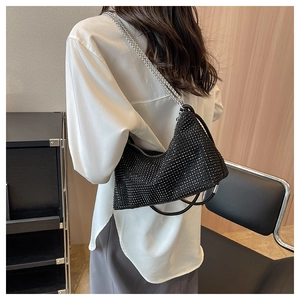 Detail of a black hobo bag with rhinestone embellishments shown on a crossbody model