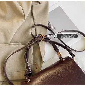 Detail view of burgundy leather shoulder bag with adjustable strap and gold metal buckle