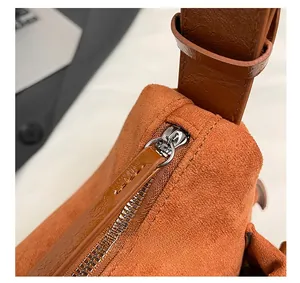 Detailed close-up of smooth silver metal zipper and brown vintage suede leather stitching