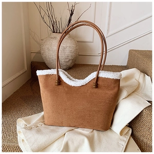 Brown faux suede tote bag with white faux shearling trim on a beige decorative background