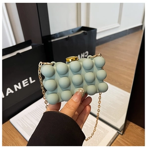 Detail of light green bubble texture acrylic clutch bag with gold chain and turn-lock