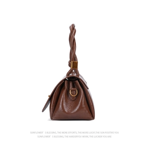 Detail of vintage brown leather handbag featuring pleated sides and braided handles
