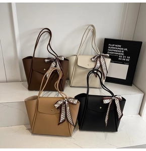 Dettaglio di quattro borse tote in pelle colorata con foulard di seta sui manici