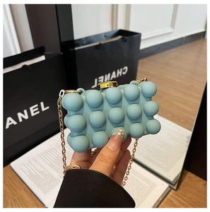 Detail of light blue bubble texture clutch bag with gold chain and clasp closure