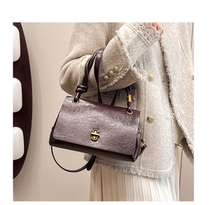 Close-up of retro oil-wax leather shoulder bag with a gold twist lock and knot strap