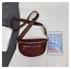Detailed top view of a brown suede crossbody bag with dual zippers and adjustable strap