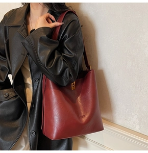 Detail einer weinroten Leder-Tote-Bag mit goldenem Drehverschluss an einem Modell