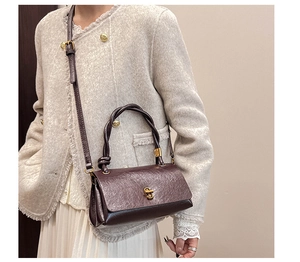 Detail of vintage brown leather bag with golden twist lock and woven handle texture