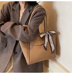 Dettaglio borsa tote in pelle color cammello con sciarpa di seta e fibbia in metallo dorato