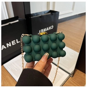 Detail of dark green clutch with 3D sphere texture and gold chain strap