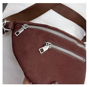 Detail view of smooth silver zippers on a dark brown suede crossbody chest bag texture