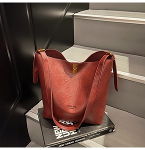 Nahaufnahme der weinroten Beuteltasche mit goldenen Beschlägen auf einem schwarzen Buch