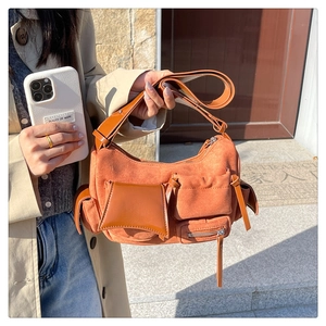 Detail of a brown suede and leather crossbody bag with multiple utility pockets