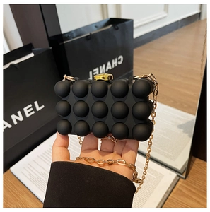 Detail of matte black bubble textured clutch bag with gold chain strap and metal lock