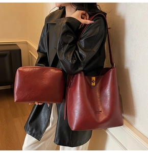 Dunkelrote Beuteltasche im Set mit kleiner Tasche und goldenem Verschluss am Model