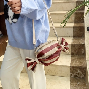 Sac bandoulière en forme de bonbon à rayures rouges et beige porté par un mannequin