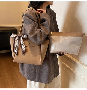 Dettaglio di un set borsa tote beige con pochette coordinata e sciarpa di seta sul manico