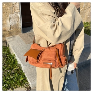 Detail of a burnt orange suede bag featuring utility pockets and long zipper pulls