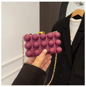 Close-up of a deep purple bubble texture box clutch bag with gold chain and clasp