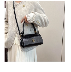 Detail of black glossy wrinkled texture handbag with a golden metallic rotary lock