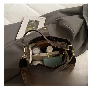 Detail view of the spacious bucket bag interior with compartments and woven wide strap