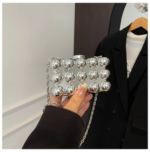 Detail of silver clutch bag featuring textured spherical patterns and a metal chain strap
