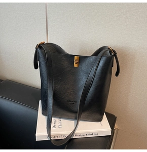 Detail der schwarzen Leder-Beuteltasche mit goldenem Drehverschluss und modischem Logo