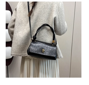 Close-up of black textured leather bag with gold hardware and stylish knotted handle