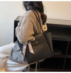 Dettaglio borsa tote in pelle nera con foulard in seta geometrico sul manico