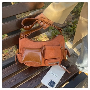 Detail of red vintage suede handbag with multiple utility pockets on a park bench