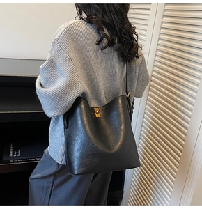 Detailaufnahme der schwarzen Leder-Beuteltasche mit goldenem Drehverschluss und Faltung