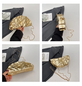 Detail view of gold metallic acrylic clutch bag with pleated texture and thin chain strap