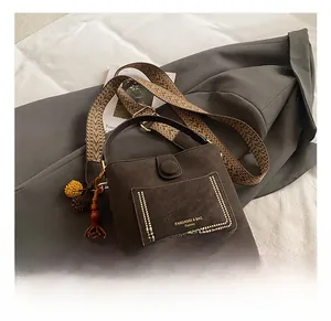 Detail of dark brown leather bucket bag with gold rivets and ethnic woven shoulder strap