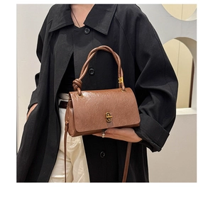 Detail of vintage brown leather handbag featuring a unique knotted handle and gold metal clasp