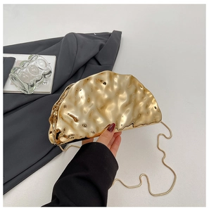 Detail of a chic gold evening clutch with modern wavy folds and a slim metal chain strap