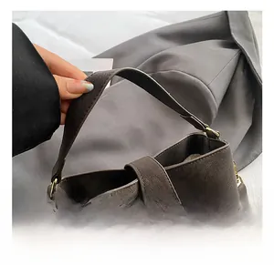 Close-up of comfortable wide handle and woven strap detail on dark brown bucket bag