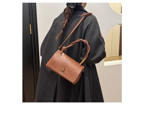 Detail of vintage brown leather bag showing texture, knot handle and golden metal clasp