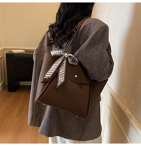 Dettaglio macro della borsa tote in pelle marrone con sciarpa di seta decorativa stampata