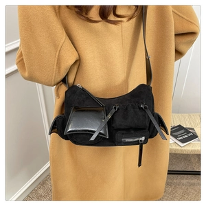 Detailed view of a black multi-pocket crossbody bag worn with a classic camel coat