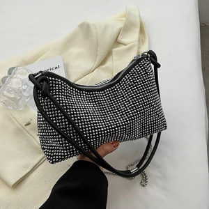 Sparkling black rhinestone shoulder bag with metal chain on a white blazer background