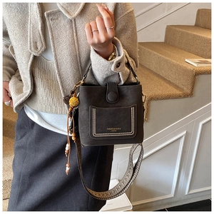Detail of dark brown bucket bag with pearl trim on pocket and woven shoulder strap