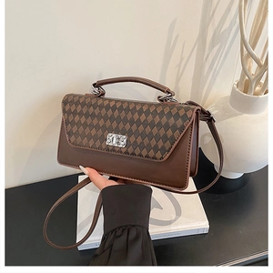 Macro detail of brown leather bag featuring quilted pattern and shiny crystal buckle