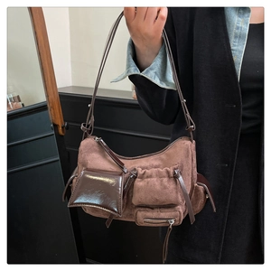 Detailed view of brown suede satchel with multiple functional pockets and leather accents