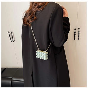 Detail of light blue bubble texture crossbody bag with gold chain on black blazer