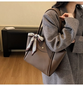 Dettaglio borsa tote in pelle marrone a grana con foulard decorativo in seta a stampa H