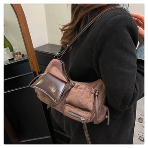 Detail of a brown suede vintage shoulder bag with multi-pocket utility design and zip