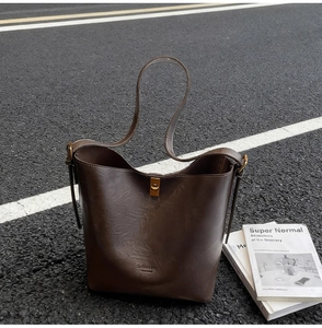 Detailansicht der dunkelbraunen Leder-Beuteltasche mit goldenem Drehverschluss und Narbung