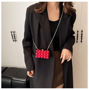 Detail of red bubble texture acrylic mini bag with elegant gold chain strap on model