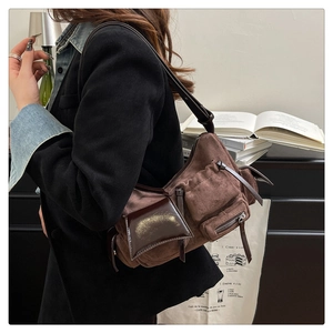 Detail of vintage brown suede crossbody bag featuring multi-pocket design and leather straps