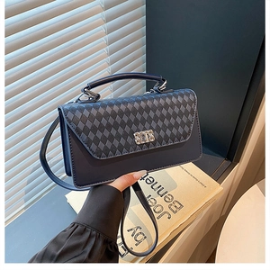 Detail of navy blue quilted crossbody bag featuring a silver rectangular twist lock closure
